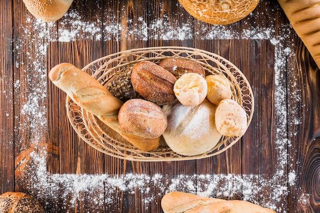 Cesta de panes de pan dentro del marco rectangular hecha con harina en la mesa de madera
