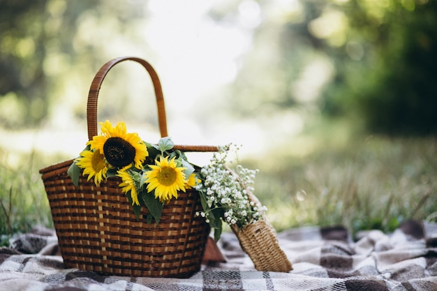 Cesta de picnic con frutas y flores en manta