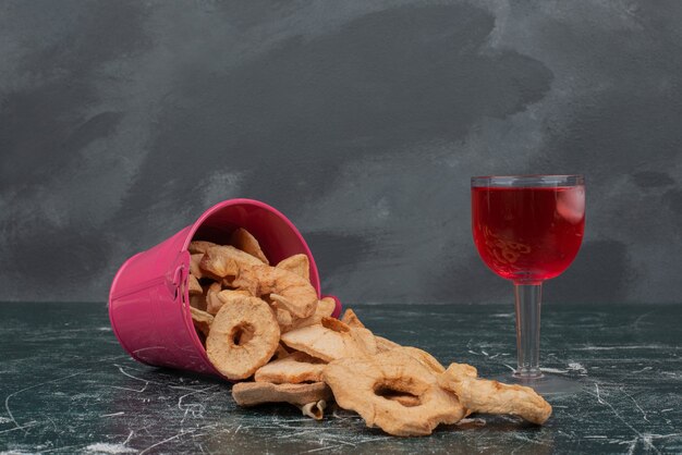 Cesta rosa con frutos secos y vaso de jugo en la pared de mármol.