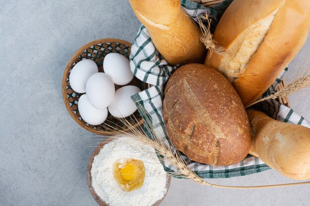 Cesta de varios panes junto con harina y huevos. Foto de alta calidad