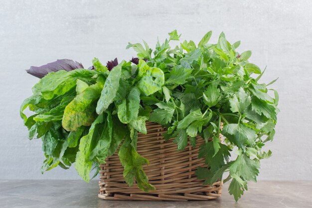 Cesta de verduras recién recogidas y lavadas sobre mármol.