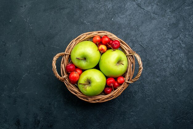 Cesta de la vista superior con frutas manzanas y cerezas dulces en la superficie oscura del árbol de frescura de composición de bayas de frutas