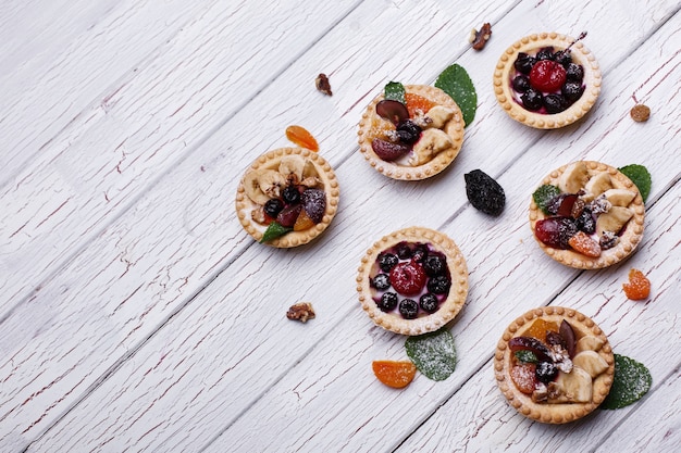 Cestas deliciosas de frutas al horno con bayas, frutas exóticas, vegetación y nueces