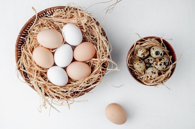 cestas llenas de huevos en nidos en mesa blanca