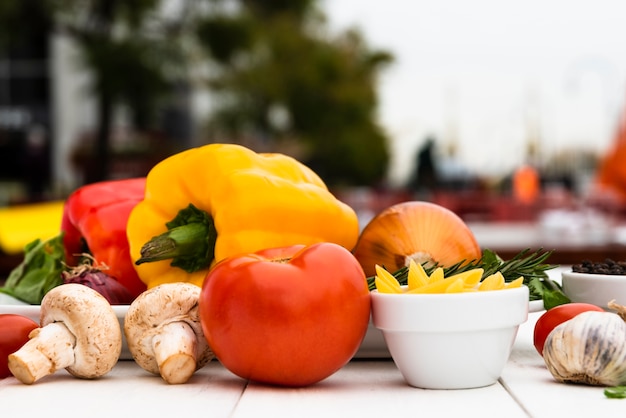 Foto gratuita champiñones crudos; tomate; pimientos; ajo; cebolla; en el escritorio blanco