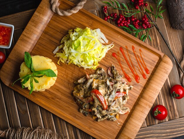 Champiñones de pollo frito con verduras sobre tabla de madera