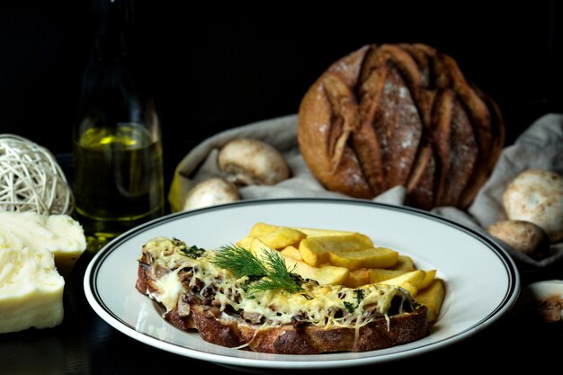 Champiñones salteados cubiertos con queso derretido sobre tostadas marrones, servidos con papas fritas