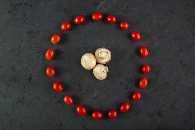 Champiñones y tomates champiñones maduros junto con tomates cherry suaves de forma redonda sobre piso gris