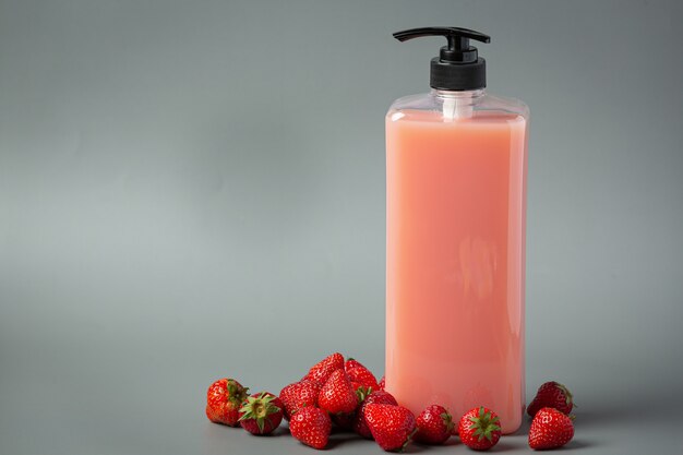 Champú de fresa botella cosmética sobre superficie blanca