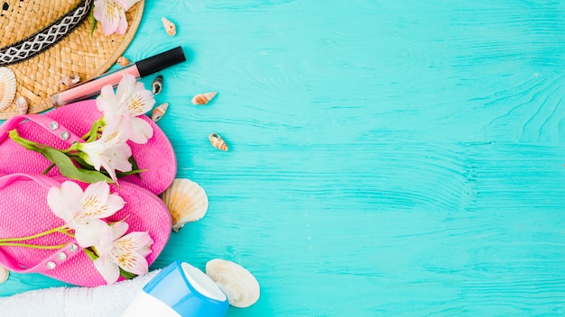 Foto gratuita chanclas cerca del sombrero entre flores con conchas y lápiz labial