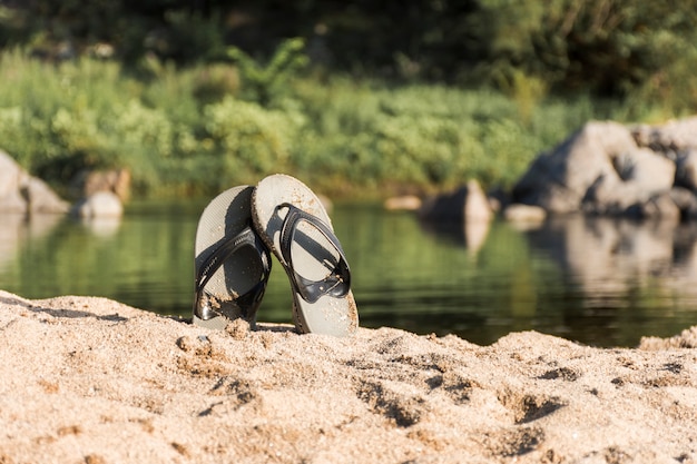 Chanclas en la costa de arena cerca del agua