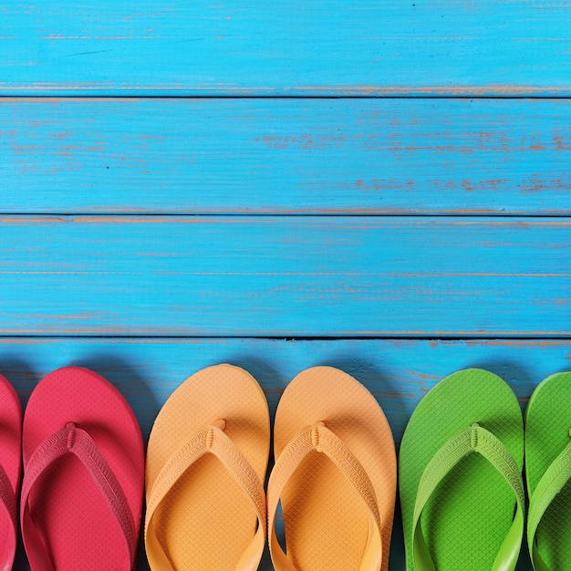 Chanclas en una fila de fondo de madera de playa azul