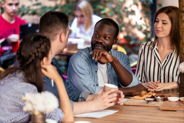 Charlando con los mejores amigos en el acogedor restaurante al aire libre en el cálido día de verano