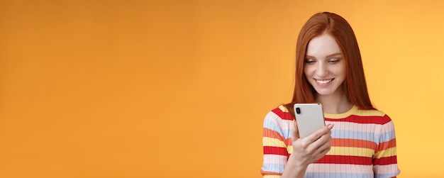 Foto gratuita charming moderna pelirroja estudiante de la universidad comprobando la caja de mensajes con el teléfono inteligente parecer feliz