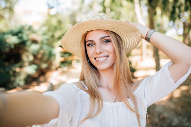 Cheert. Hora de hacerse un selfie. Jovencita feliz en unas vacaciones de primavera, caminando en la ciudad fotografiándose a sí misma en un día soleado