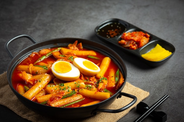 Cheesy Tokbokki comida tradicional coreana sobre fondo de tablero negro. Plato de almuerzo.