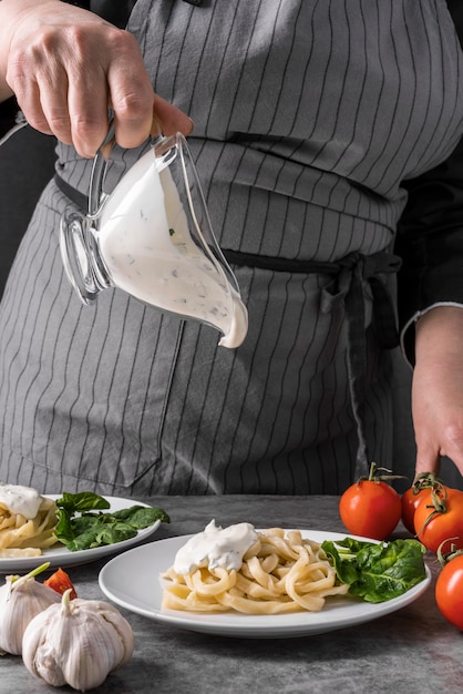 Foto gratuita chef agregando aderezo al plato de pasta