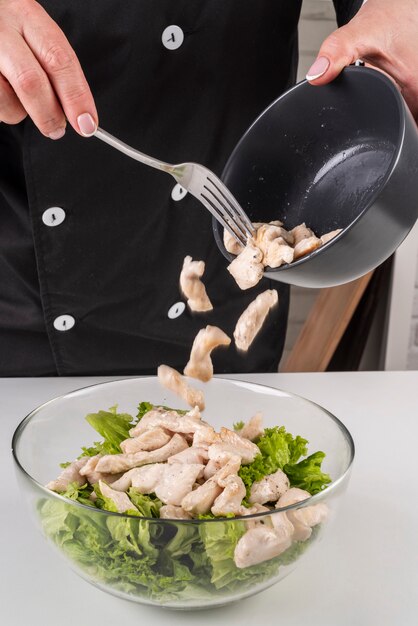 Chef agregando carne a la ensalada