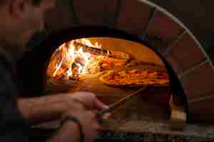 Foto gratuita chef de alto ángulo horneando pizza en horno de leña