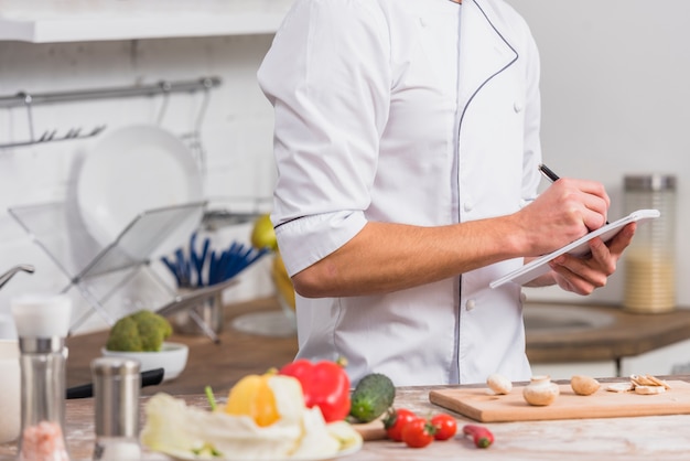 Chef en cocina escribiendo notas