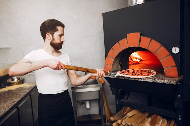 Chef en la cocina prepara pizza.