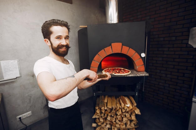 Chef en la cocina prepara pizza.