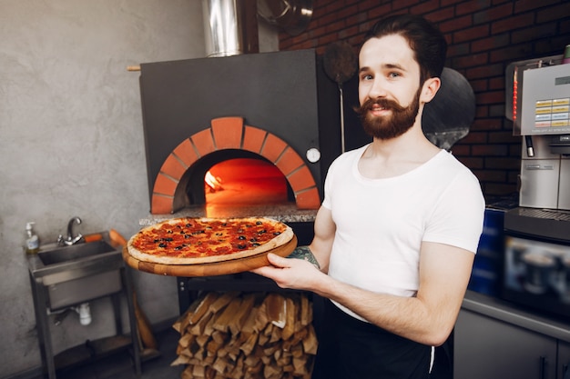 Chef en la cocina prepara pizza.