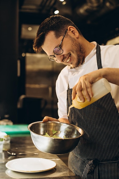 Chef de cocina en un restaurante agregando salsa a la ensalada