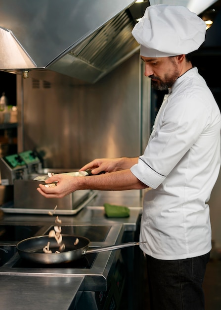 Foto gratuita chef cocinando en la cocina mientras lleva ropa profesional