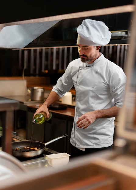 Foto gratuita chef cocinando en la cocina mientras lleva ropa profesional