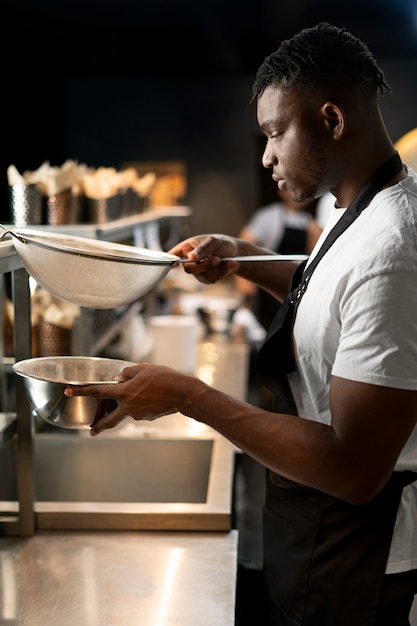 Foto gratuita chef cocinando en la cocina mientras lleva ropa profesional