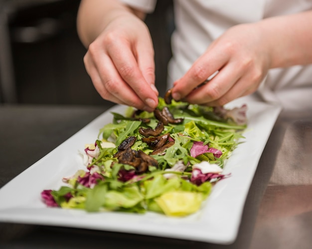 Chef colocando champiñones en ensalada