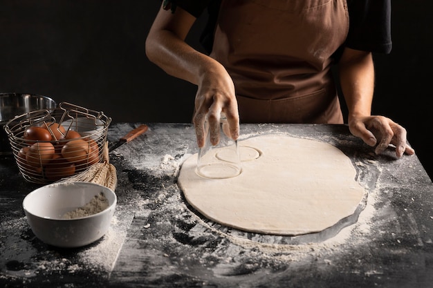 Chef cortando un círculo de masa sobre la mesa