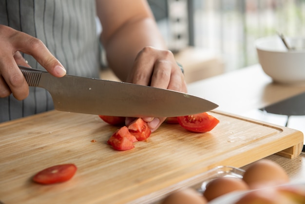 Chef cortando tomates en tabla de cortar