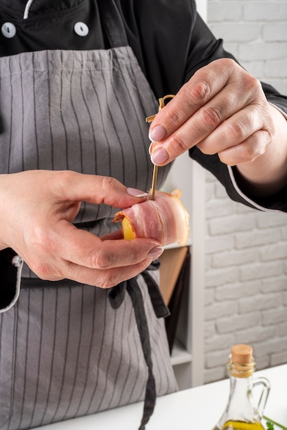 Chef envolviendo tocino alrededor de fruta