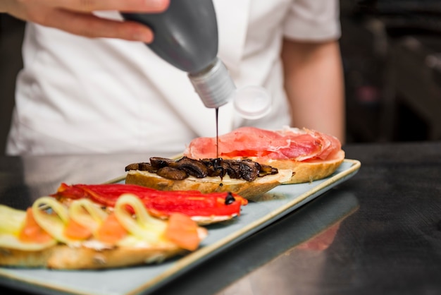 Chef exprimiendo salsa en bruschetta