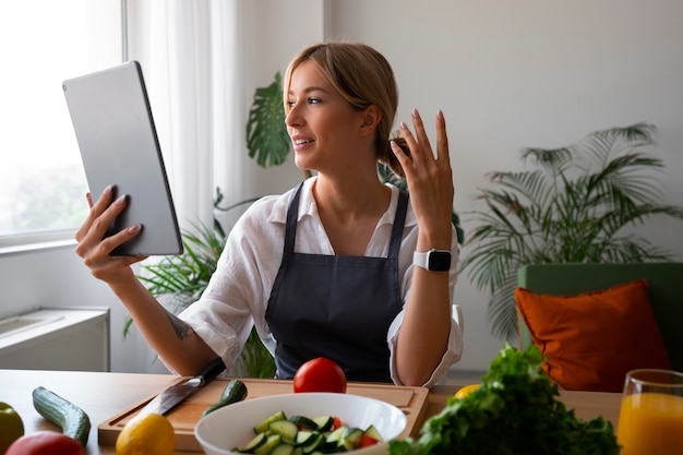 Foto gratuita chef femenina teniendo una videollamada mientras cocina