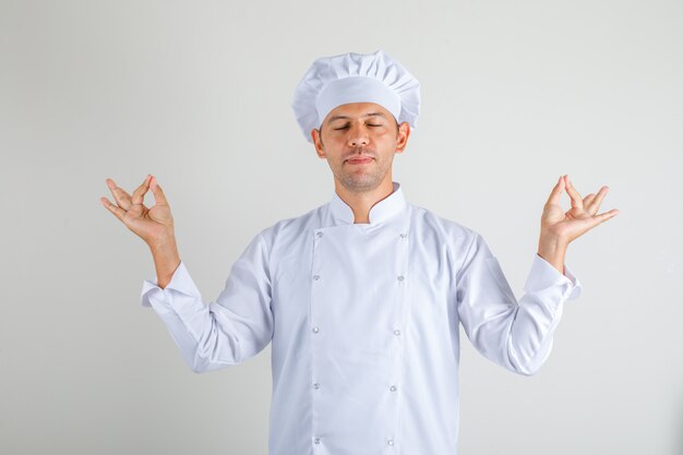 Chef hombre cocinero haciendo gesto de meditación con los ojos cerrados en uniforme y sombrero