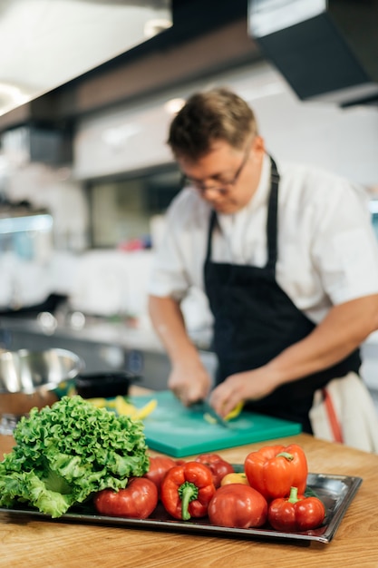 Chef hombre Defocused cortando verduras