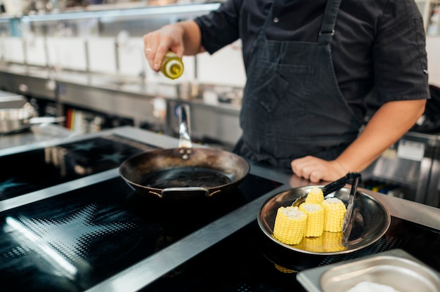 Chef hombre con delantal añadiendo aceite a la sartén