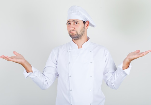 Chef hombre mostrando gesto de impotencia en uniforme blanco y mirando confundido