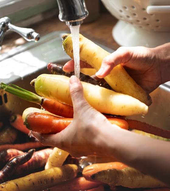 Chef limpiando zanahorias y nabos en el fregadero