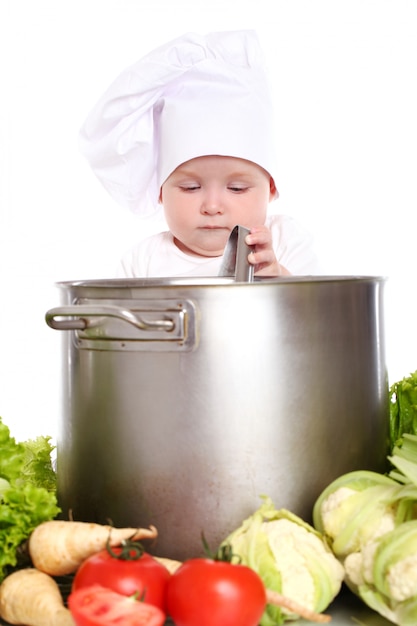 Chef lindo bebé con olla grande y verduras