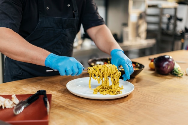 Chef macho con guantes poniendo pasta en un plato