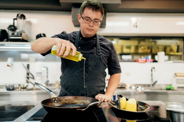 Chef masculino añadiendo aceite en sartén