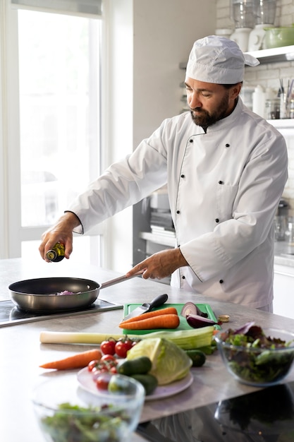 Foto gratuita chef masculino en la cocina cocinando un plato en una sartén