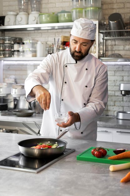 Chef masculino en la cocina cocinando un plato en una sartén