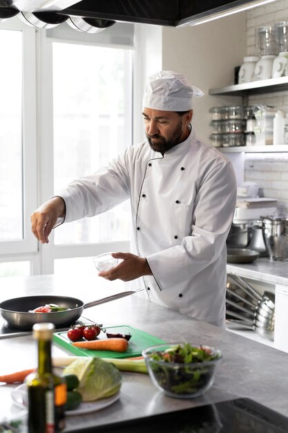 Chef masculino en la cocina cocinando un plato en una sartén
