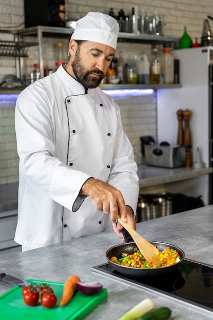 Chef masculino en la cocina cocinando un plato en una sartén