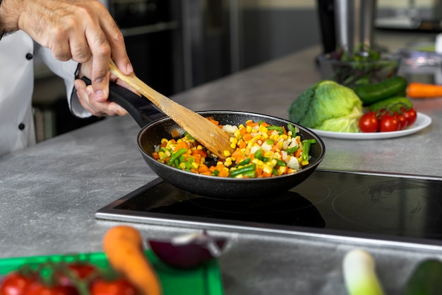 Chef masculino en la cocina cocinando un plato en una sartén